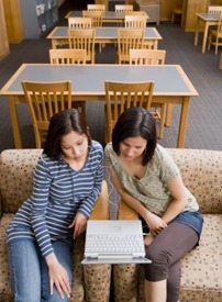Two students/ friends looking at laptop computer together.