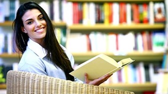 stock-footage-smiling-female-student-with-book-sitting-in-a-chair-in-a-bookstore